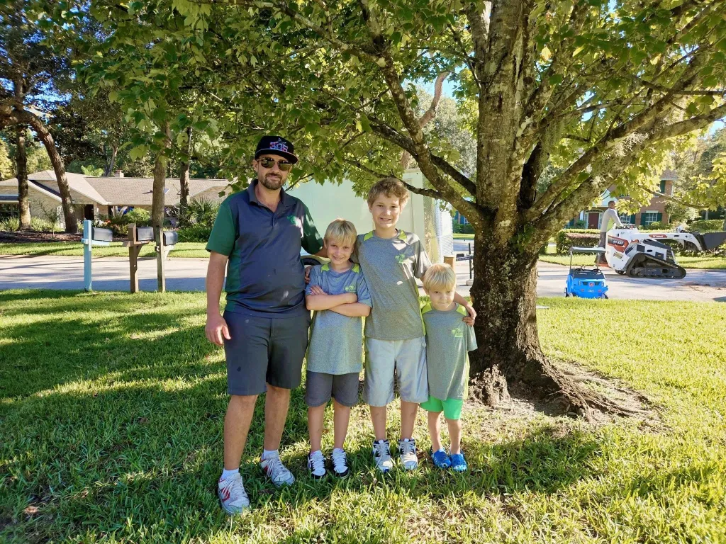 Mic Smith with his family beside landscaping equipment