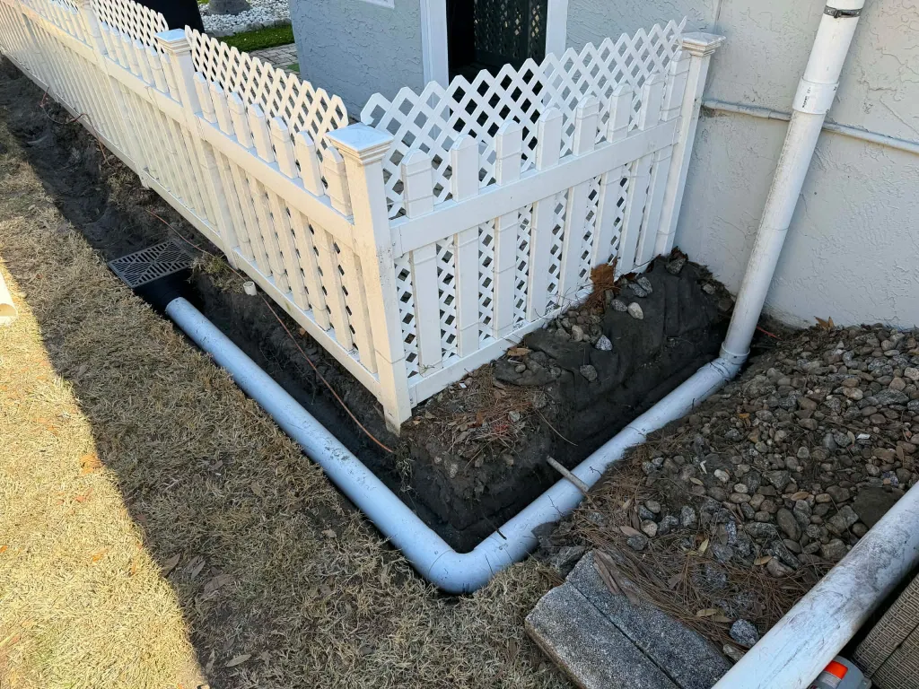 Drainage piping being installed around a fenced side yard