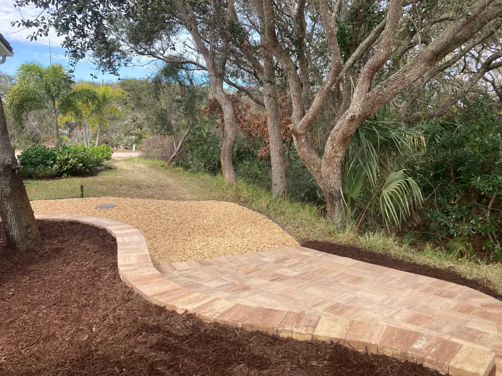 Curved paver path connecting a landscaped backyard area