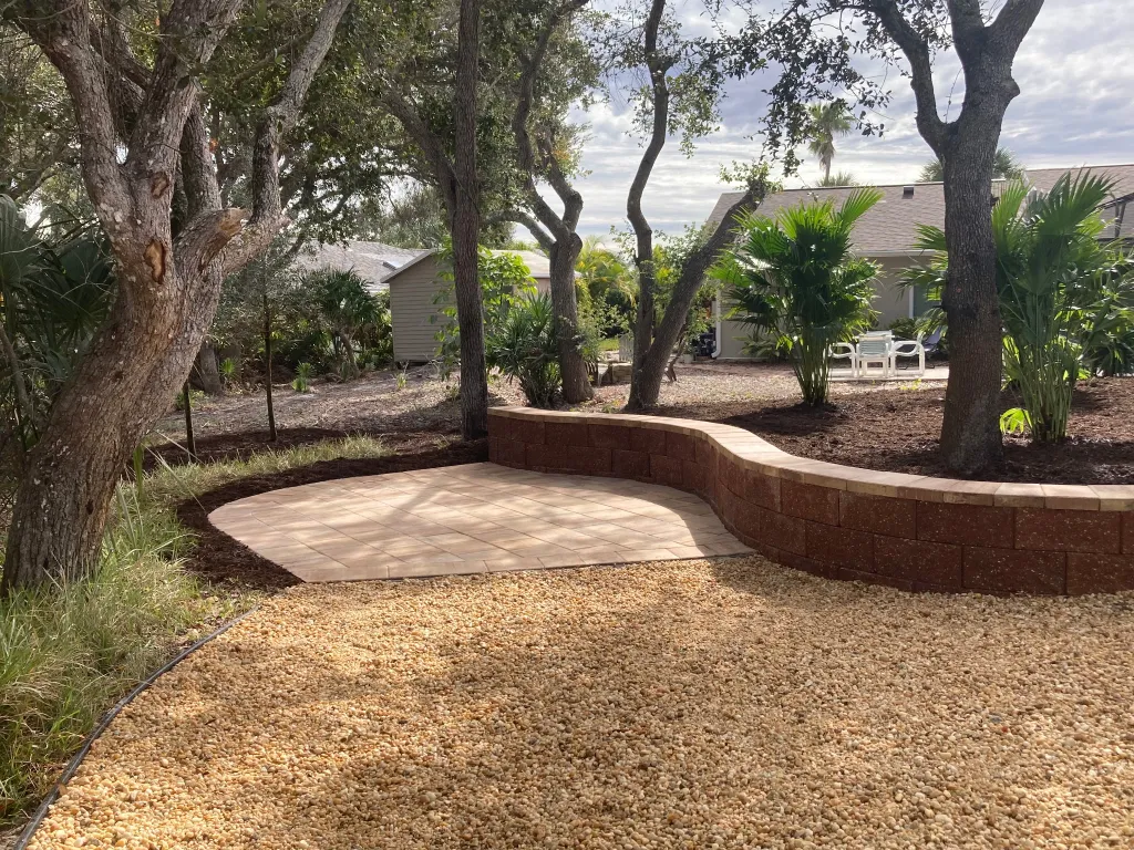 Curved paver area with a matching retaining wall and landscaped beds